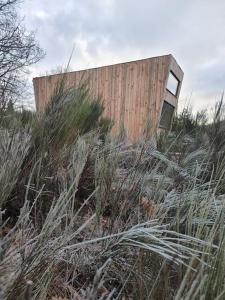 een houten gebouw op een heuvel met hoog gras bij Moose Home Genêts in Cros