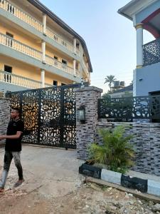 a boy walking in front of a building with a gate at Paviosca Hotel in Umuahia