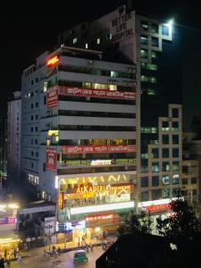 a tall building with neon signs in a city at night at Hotel Rose Garden Palace Residential in Dhaka