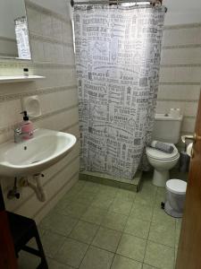 a bathroom with a sink and a toilet and a shower curtain at KIRIKOS ROOMS in Sifnos