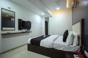 a bedroom with a bed with a tv on the wall at OYO Hotel Dream Inn in Sarkhej