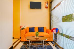 uma sala de estar com um sofá laranja e uma mesa em FabExpress Kurla Inn em Mumbai