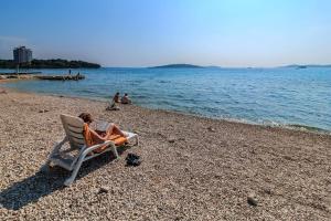 una persona seduta su una sedia in spiaggia di Apartments and Rooms Bozena a Vodice