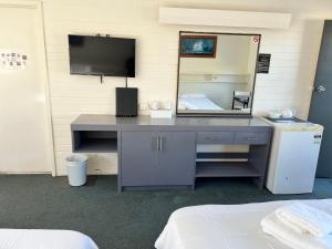 una scrivania con TV e specchio in una stanza di Bairnsdale Town Central Motel a Bairnsdale