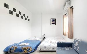 a white bedroom with a bed and a chair at บ้านสวัสดี Bann Sawasdee in Ban Sai Mai