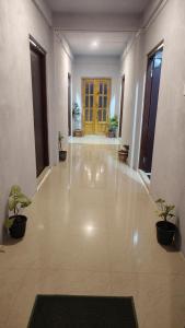 an empty hallway with potted plants and a yellow door at Breeze Hills Inn in Cherrapunji