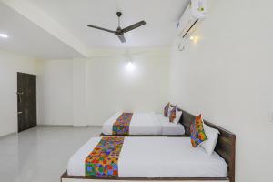 2 Betten in einem weißen Zimmer mit einer Decke in der Unterkunft FabExpress Park View in Rāipur