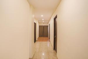 un corridoio con pareti bianche e pavimenti e porte piastrellati. di FabExpress Park View a Rāipur
