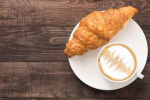 een bord met een kopje koffie en een croissant bij Hotel Global Radiance plaza Delhi Airport in New Delhi