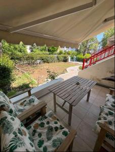 a patio with a wooden table and a bench at Glifa Beach House Maisonette in Glida