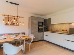 Modern Apartment in Kirchdorf with Garden في كيرشدورف في تيرول: مطبخ مع طاولة خشبية ودواليب بيضاء