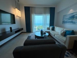 a living room with a couch and a tv at 1 Bed Apartment-Rixos Fairmont Residences in Abu Dhabi
