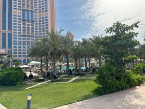 a park with palm trees and buildings in the background at 1 Bed Apartment-Rixos Fairmont Residences in Abu Dhabi