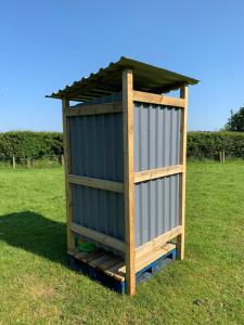 a wooden outhouse with a roof on a grass field at Rescorla Retreats - Wisteria in St Austell