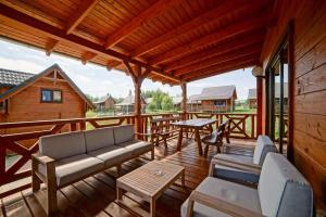 a wooden deck with a couch and tables on it at Domki cało roczne z własnym stawem nad jeziorem in Ryn