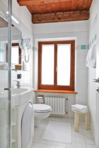 La salle de bains blanche est pourvue de toilettes et d'un lavabo. dans l'établissement Albergo All'Ancora, à Garde