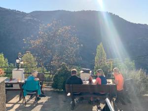 a group of people sitting at tables in front of a mountain at Hotel los Bérchules in Bérchules