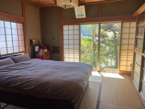 ein Schlafzimmer mit einem Bett und zwei großen Fenstern in der Unterkunft NONAGASE GUEST HOUSE 