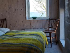 een slaapkamer met een bed, een stoel en een raam bij Guesthouse Nýp in Nýp
