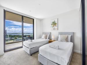 2 camas en una habitación con ventana grande en Sweeping Ocean view Apt w Carpark and rooftop pool, en Gold Coast