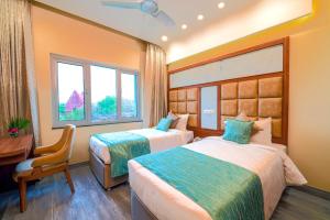 a hotel room with two beds and a desk and window at Ramoji Film City- Tara Comfort Hotel in Pedda Ambarpet