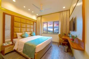 a bedroom with a bed and a desk and a window at Ramoji Film City- Tara Comfort Hotel in Pedda Ambarpet