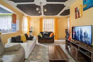 a living room with a couch and a flat screen tv at Spacious 2-BR Apartment In Membley in Ruiru