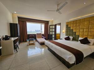 a hotel room with a large bed and a desk at Hotel Grand Darshan Vadodara in Vadodara