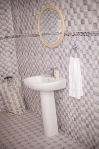 een badkamer met een witte wastafel en een spiegel bij Kim's Guest House in Kasoa