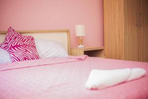 - une chambre rose avec un lit et un oreiller blanc dans l'établissement Kim's Guest House, à Kasoa