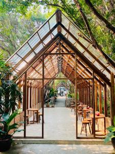 a wooden pavilion with tables and chairs and trees at Ngeeb bed and EV station in Chiang Rai