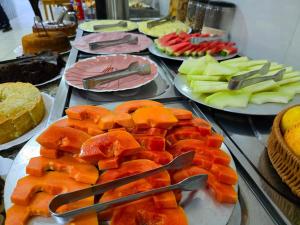 a buffet of fruit on plates with forks and knives at Pousada Santa Gianna in Aparecida