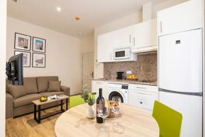 uma cozinha e sala de estar com uma mesa e um sofá em Precioso apartamento a 2 minutos de El Retiro em Madri