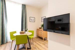uma sala de estar com uma mesa e uma grande televisão na parede em Precioso apartamento a 2 minutos de El Retiro em Madri