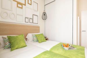 a bedroom with a white bed with green pillows at Apartamentos Blume Conde Aranda in Madrid