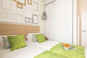 a bedroom with a white bed with green pillows at Precioso apartamento a 2 minutos de El Retiro in Madrid