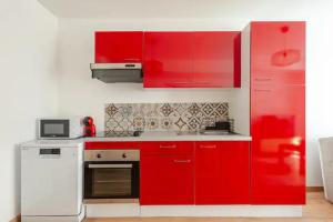 een rode keuken met witte apparaten en rode kasten bij L'escale des vignobles in Gevrey-Chambertin