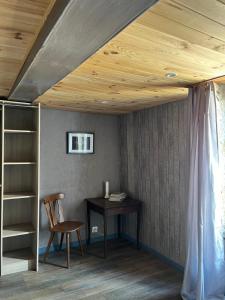 einen Schreibtisch und einen Stuhl in einem Zimmer mit Holzdecke in der Unterkunft Gîte Pierre et Meuse in Fumay