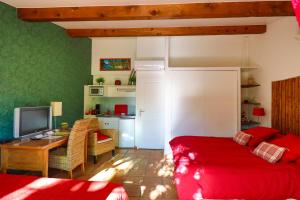 a bedroom with a red bed and a desk with a television at Le Mas de Bertagne in Gémenos
