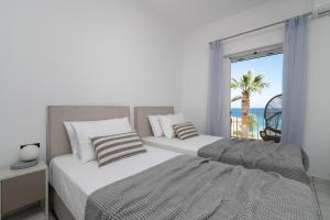 two beds in a bedroom with a view of the ocean at Swan Apartments in Zakynthos Town