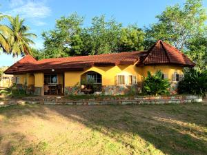 a yellow house with a red roof at Rent your own private beach bungalow in Ampeni