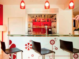 a bar with two chairs and a counter with bottles at ibis Senlis in Senlis