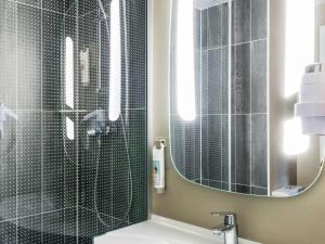 La salle de bains est pourvue d'une douche avec un miroir et un lavabo. dans l'établissement ibis Senlis, à Senlis