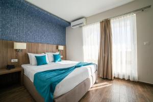 een hotelkamer met een groot bed met blauwe accenten bij Hotel Sato in Sutomore