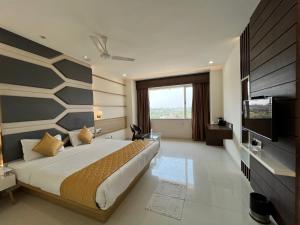 een slaapkamer met een groot bed en een televisie bij Hotel Grand Darshan Vadodara in Vadodara