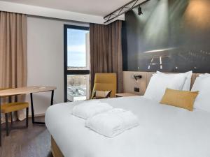 ein Hotelzimmer mit einem großen weißen Bett und einem Schreibtisch in der Unterkunft Mercure Montpellier Centre Comédie in Montpellier