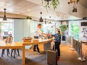 un hombre y una mujer preparando comida en una cocina en ibis Colmar Est - Hotel Restaurant en Alsace en Colmar