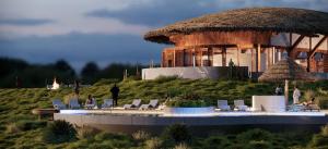 a resort with chairs and a large building with a straw roof at Serengeti Ark Safari Lodge - Kogatende in Serengeti National Park