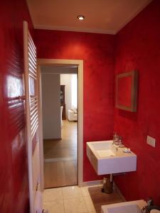 Un baño con lavabo y pared roja. en Appartamento Vissi D'Arte, en Lucca 20 fotos más