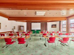 ein Klassenzimmer mit Tischen und roten Stühlen in einem Raum in der Unterkunft Mercure Hotel Bad Duerkheim An Den Salinen in Bad Dürkheim